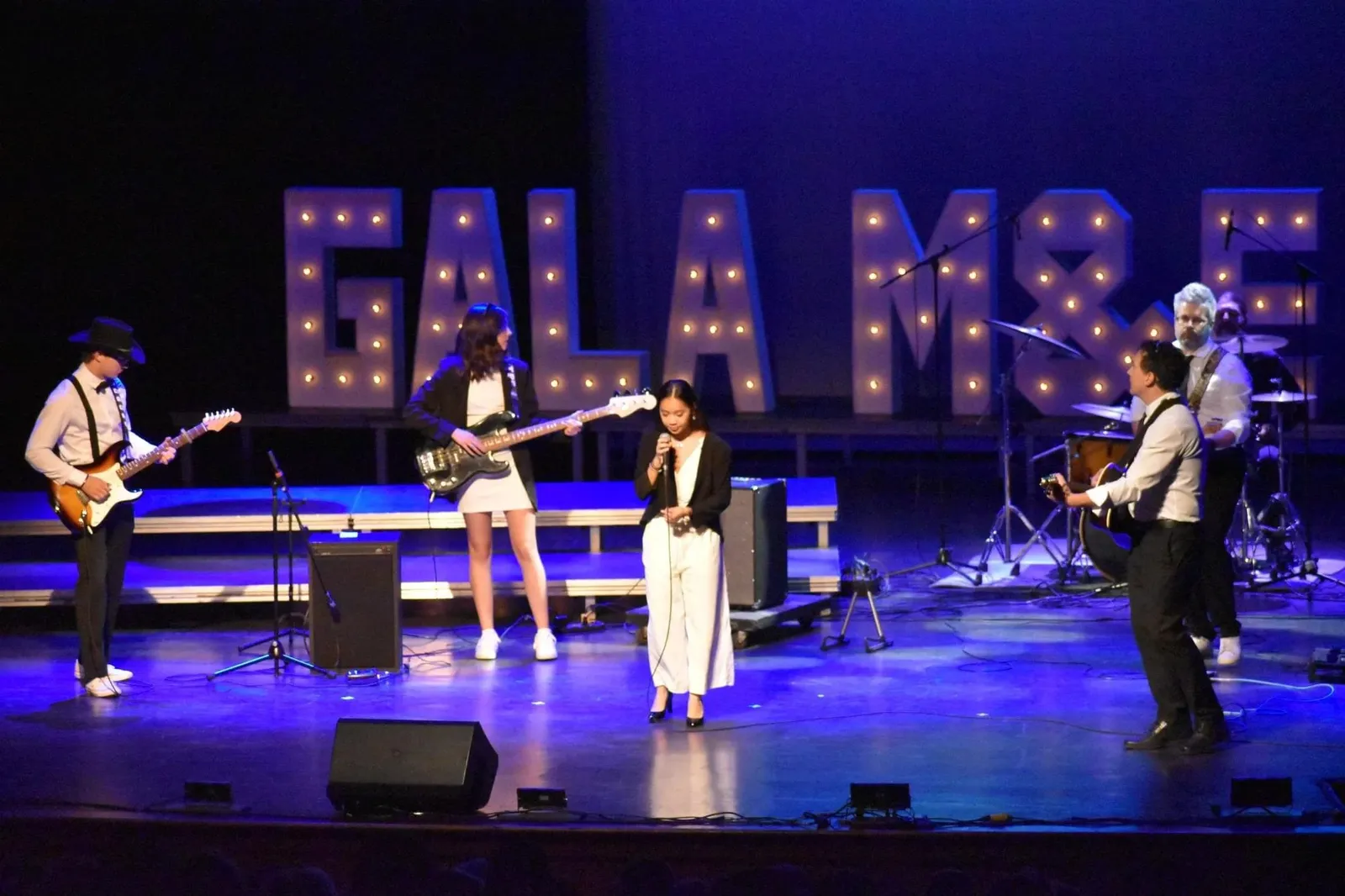 Skylar Keen singing on stage with a live band at a gala event